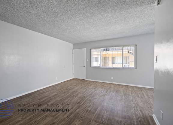 the living room of an apartment with wood flooring and a window