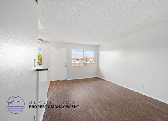 an empty living room with wood flooring and a window