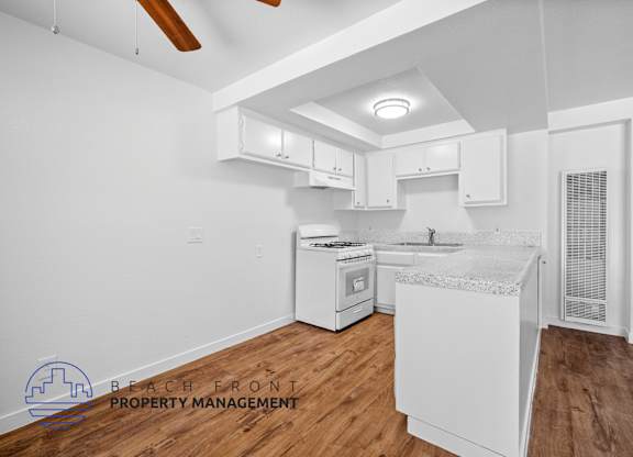 A kitchen with white cabinets and a wooden floor.