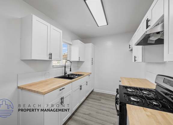 A kitchen with white cabinets and a wooden countertop.