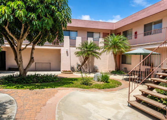 A courtyard with a tree, a bench, and a staircase.