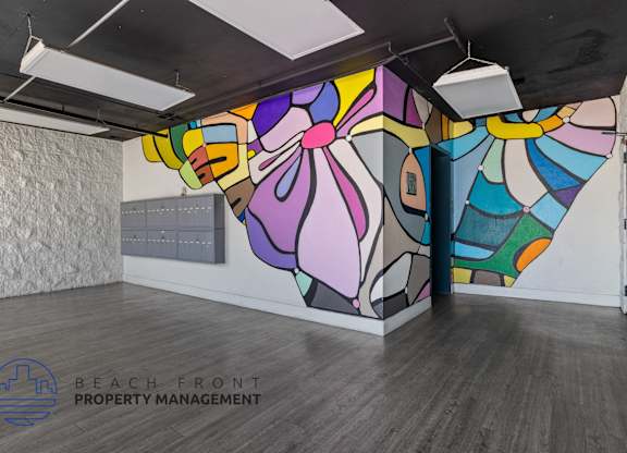 A colorful mural on the wall of a room with wooden flooring and a logo for Beach Front Property Management.