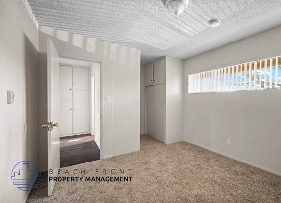 an empty room with a door to a closet and a window