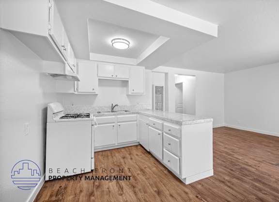 a white kitchen with a wooden floor and white cabinets