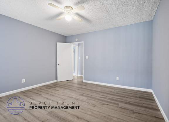 A room with a ceiling fan and a door leading to another room.