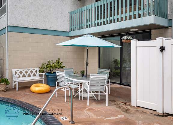 A poolside patio with a white table and chairs.