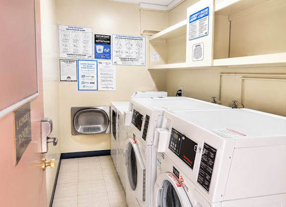 A laundromat with washers and dryers and instructions on the wall.