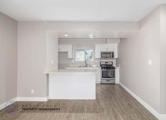 A kitchen with a white island and wooden floors.