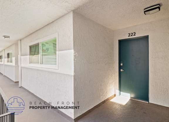 A hallway with a door numbered 222 and a window with green blinds.