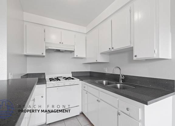 a white kitchen with white cabinets and black counter tops