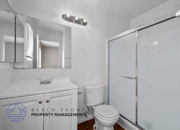 A white bathroom with a toilet, sink, and mirror.