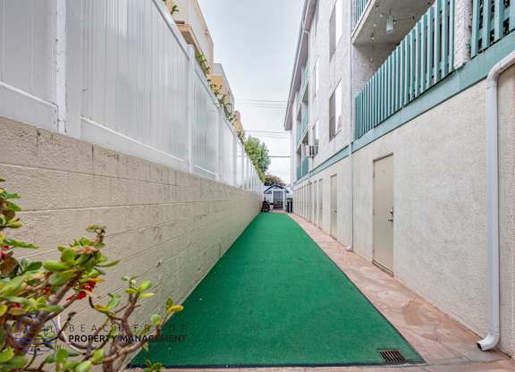 A narrow alley with a green pathway and white walls.