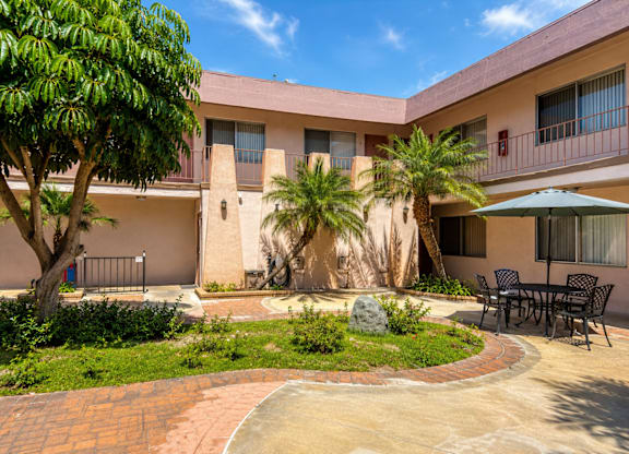 A courtyard with a table and chairs surrounded by a building.