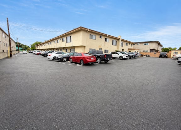 A parking lot with cars and apartment buildings in the background.