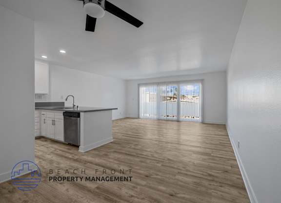 A spacious room with a kitchen area and a ceiling fan.
