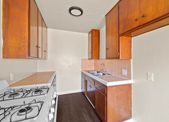 A kitchen with a stove top oven and wooden cabinets.