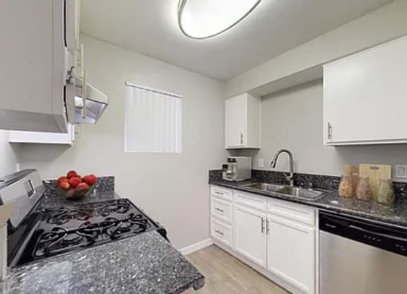 A kitchen with a black stove top and white cabinets.