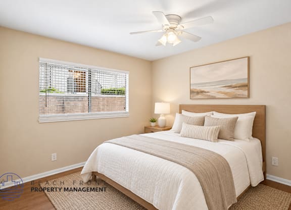 A bedroom with a large bed and a painting of a beach scene on the wall.