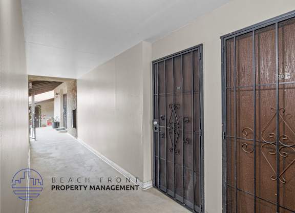 A hallway with a metal gate on the right and a wooden gate on the left.