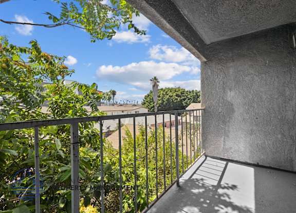 A balcony with a metal railing and a concrete wall.