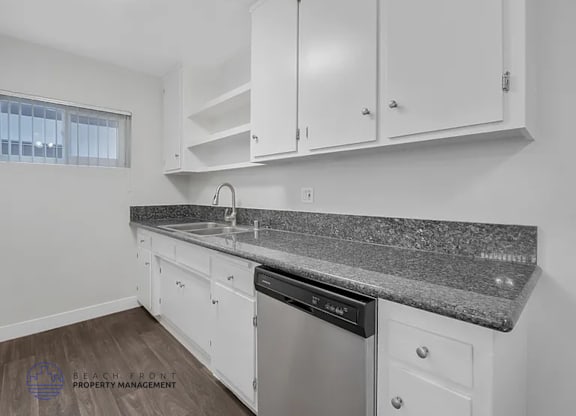 A kitchen with white cabinets and a granite countertop.
