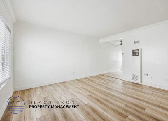 A room with wooden flooring and a logo for Beach Front Property Management.
