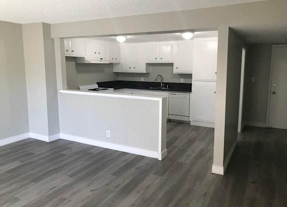 A kitchen with white cabinets and a grey floor.