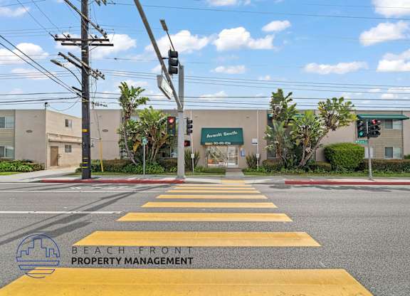 A street view with a yellow crosswalk and a sign for Beachfront Property Management.