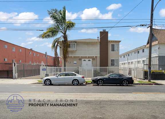 Two cars parked in front of a building with a palm tree and a sign that says