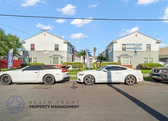 Three white cars are parked in front of a building with a sign that reads