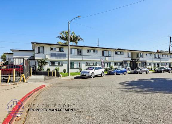 A parking lot with cars and a building with the words Beach Front Property Management.