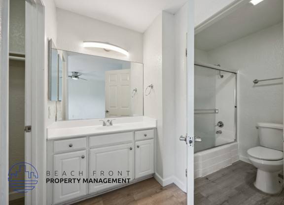 A bathroom with a white toilet and a white sink with a mirror above it.
