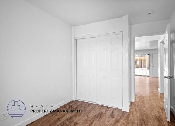 a bedroom with a white door and a hallway with a wood floor