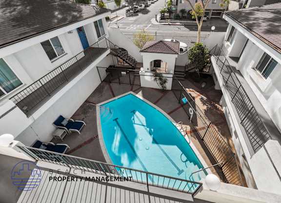 A pool surrounded by apartment buildings with a sign for beach property management.