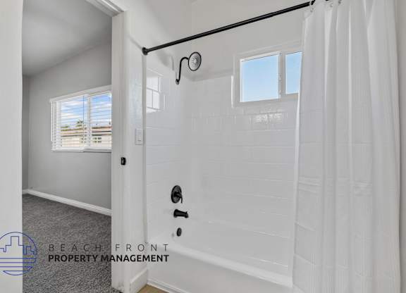 A white bathroom with a shower curtain and a window.
