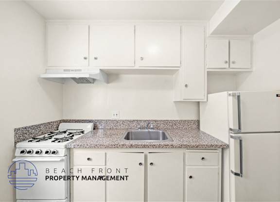 A kitchen with a stove, sink, and cabinets.