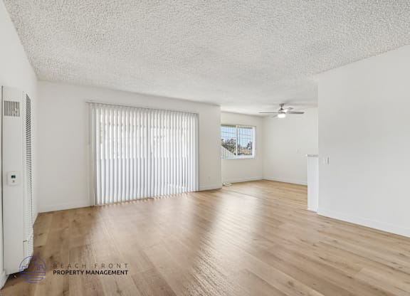 A spacious room with wooden floors and white walls.