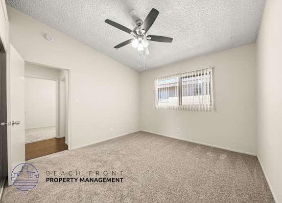A room with a ceiling fan and a window with blinds.