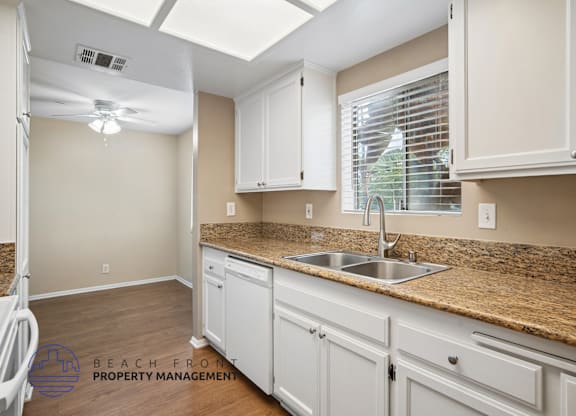 A kitchen with white cabinets and a granite countertop.