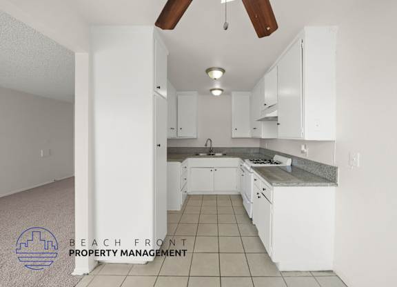 A kitchen with white cabinets and a tile floor.