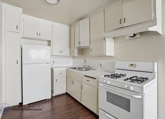A white kitchen with wooden floors and white appliances.