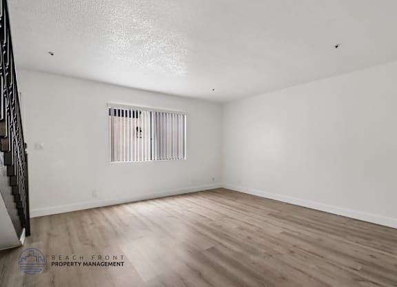 A room with wooden flooring and a window with blinds.