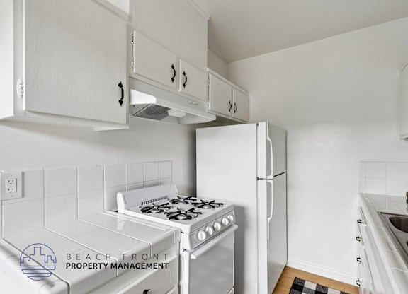 A kitchen with white cabinets and appliances.