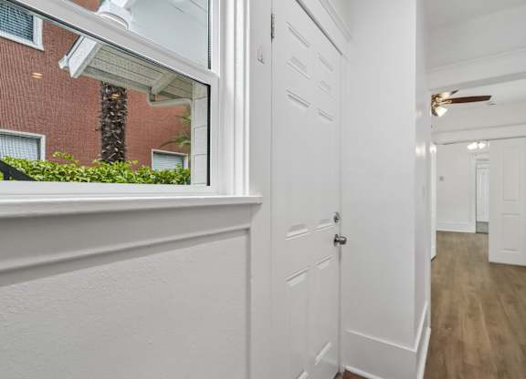 A white door is in a hallway with wood floors.