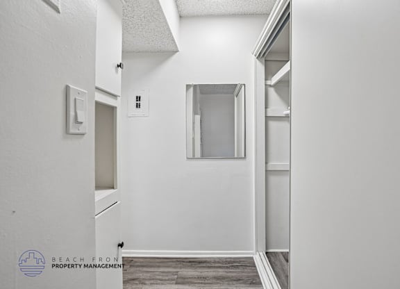 A white hallway with a door on the left and a window on the right.