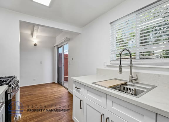 A kitchen with white cabinets and a stainless steel sink.