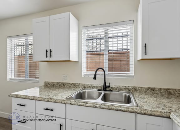 A kitchen with a granite countertop and white cabinets.
