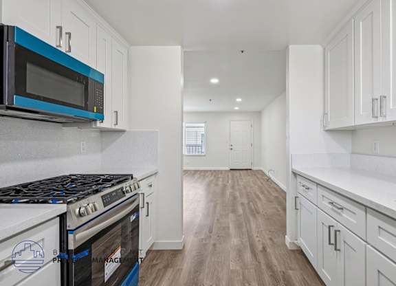 A kitchen with white cabinets and a blue and black microwave.
