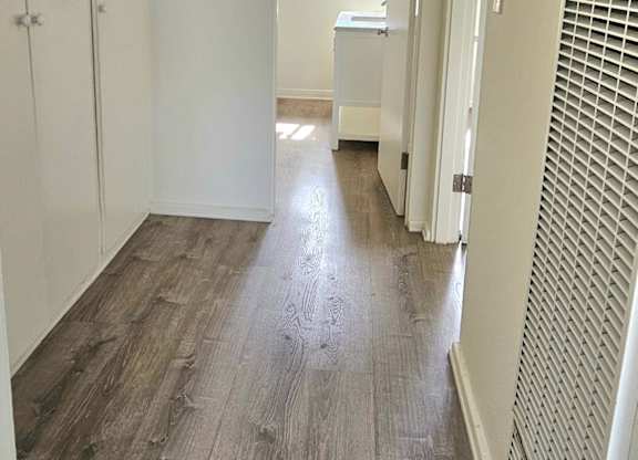 A long hallway with wood floors and white walls.