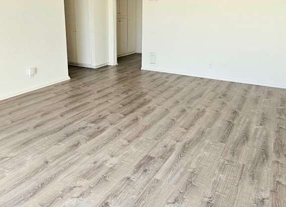 A room with a ceiling fan and wood flooring.